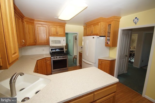 kitchen featuring white appliances, glass insert cabinets, light countertops, and a sink