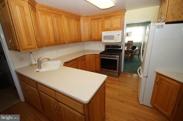 kitchen with light wood finished floors, white appliances, and light countertops