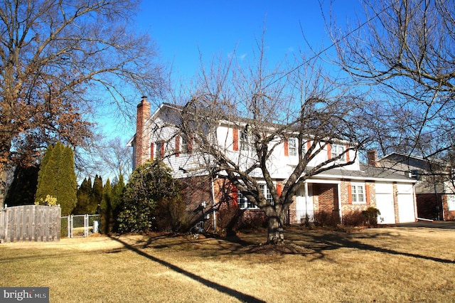 view of property exterior with brick siding, a lawn, fence, and a chimney