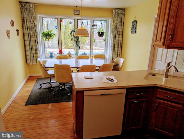 kitchen featuring dishwasher, light wood-style floors, a wealth of natural light, and a sink