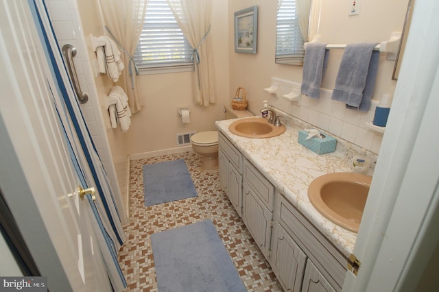 full bath featuring double vanity, decorative backsplash, toilet, and a sink