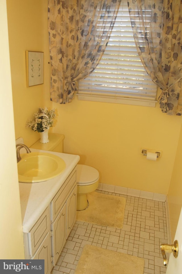 bathroom featuring baseboards, toilet, and vanity