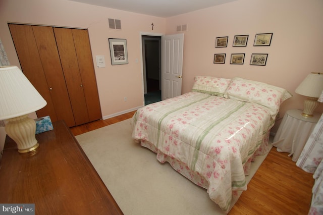 bedroom featuring light wood finished floors, baseboards, visible vents, and a closet