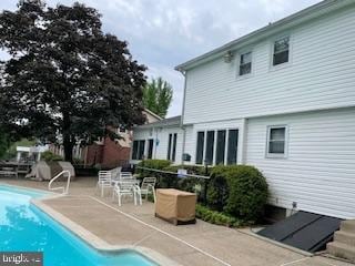 back of property with an outdoor pool and a patio