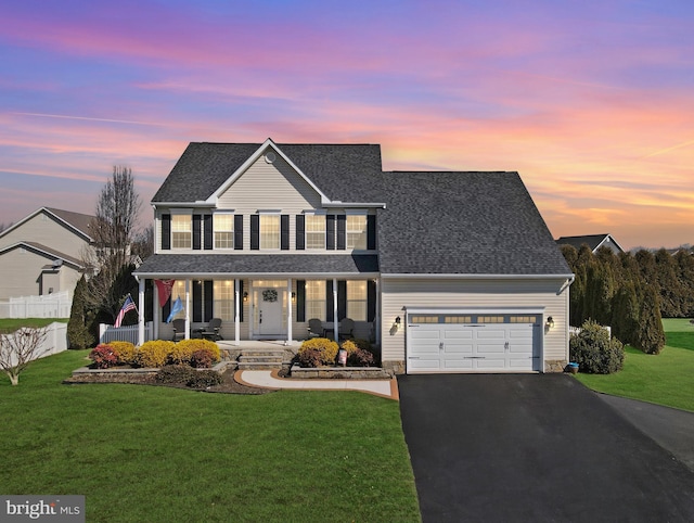 traditional-style home with covered porch, a front lawn, fence, and aphalt driveway