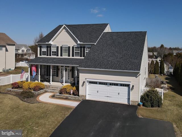 traditional-style house with a porch, roof with shingles, driveway, and fence