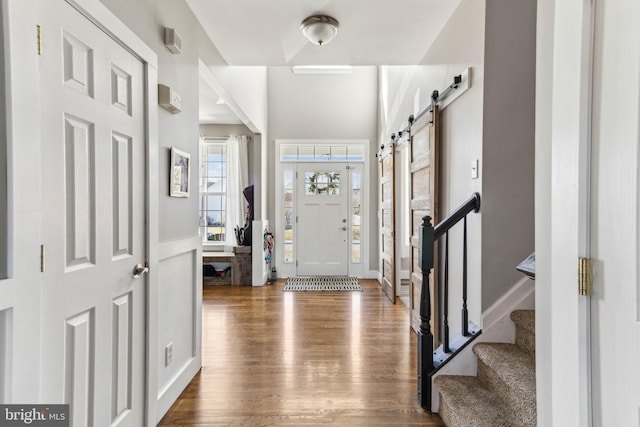 foyer featuring a barn door, stairway, and wood finished floors