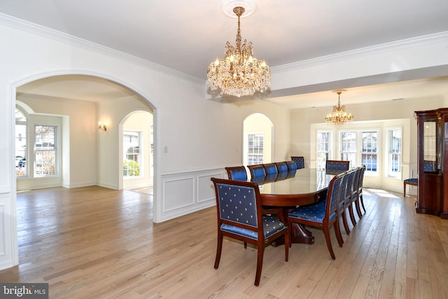 dining space with a wealth of natural light, crown molding, light wood finished floors, and an inviting chandelier