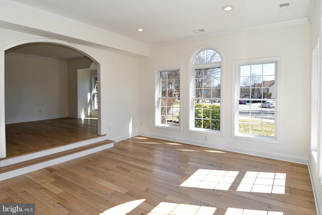 empty room featuring visible vents, a wealth of natural light, and crown molding