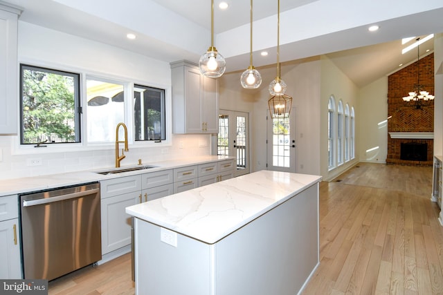 kitchen with a center island, tasteful backsplash, lofted ceiling, stainless steel dishwasher, and a sink