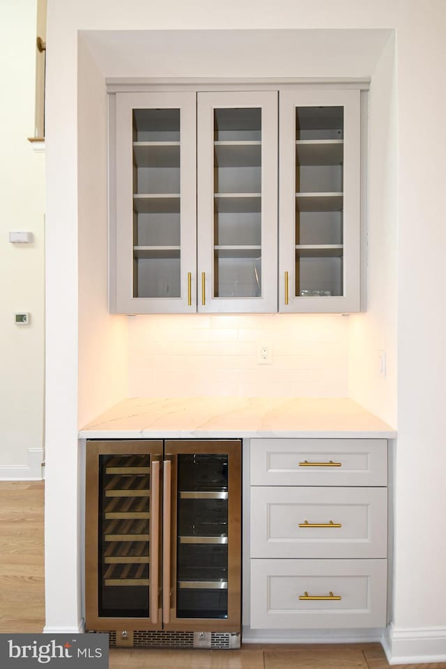 bar with wine cooler, baseboards, backsplash, and a dry bar