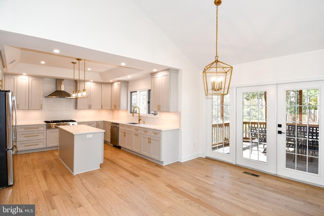 kitchen featuring visible vents, wall chimney exhaust hood, appliances with stainless steel finishes, a sink, and a notable chandelier