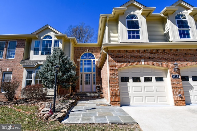 view of property featuring a garage, concrete driveway, and brick siding