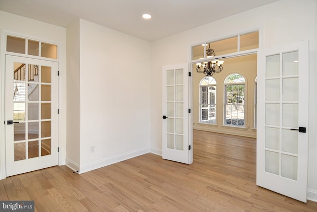 unfurnished room featuring french doors, recessed lighting, wood finished floors, a chandelier, and baseboards