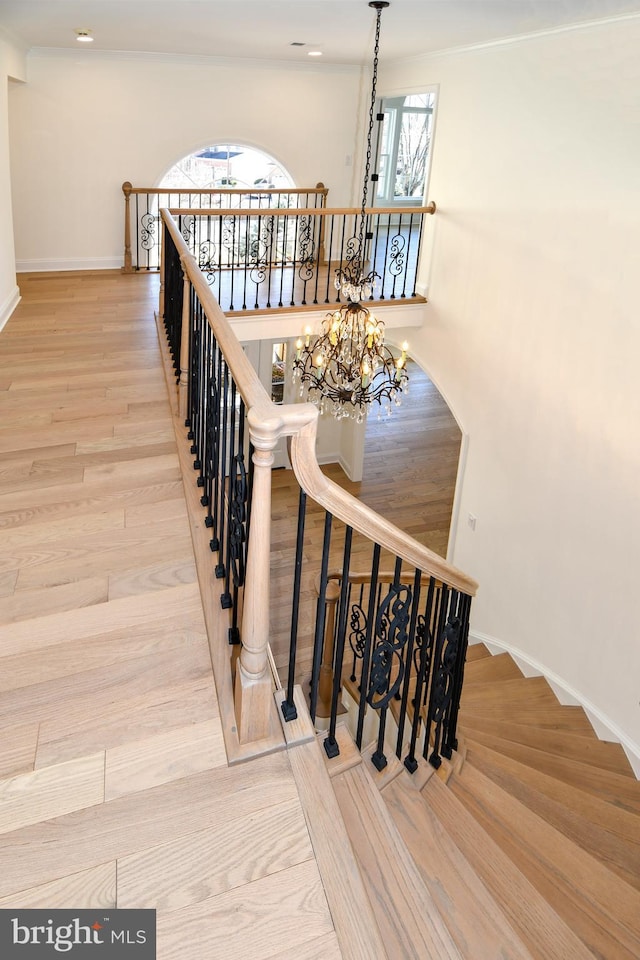 staircase featuring baseboards, a notable chandelier, and wood finished floors