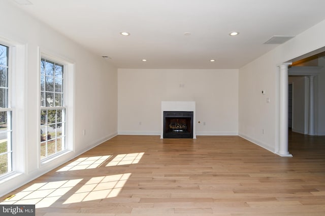 unfurnished living room featuring light wood finished floors, a fireplace, recessed lighting, and a healthy amount of sunlight