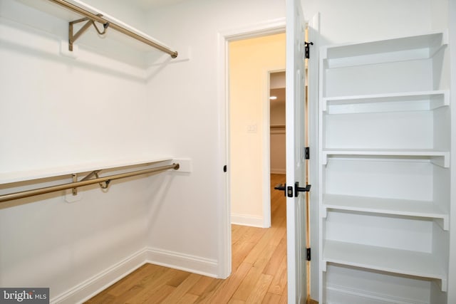 spacious closet with light wood-style flooring and a barn door