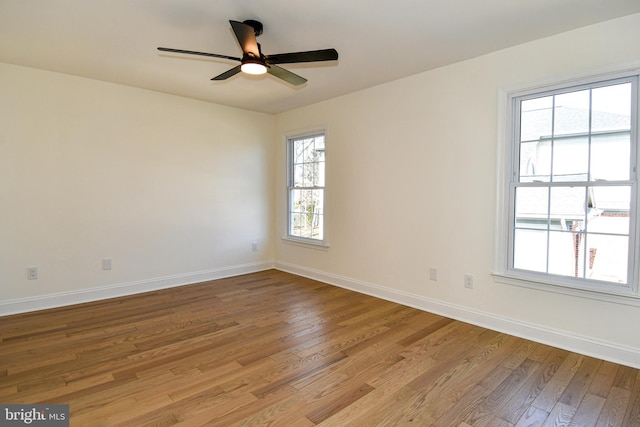 spare room featuring light wood-type flooring, ceiling fan, and baseboards