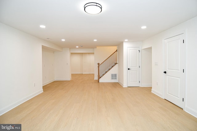 below grade area with recessed lighting, visible vents, light wood-style flooring, baseboards, and stairs