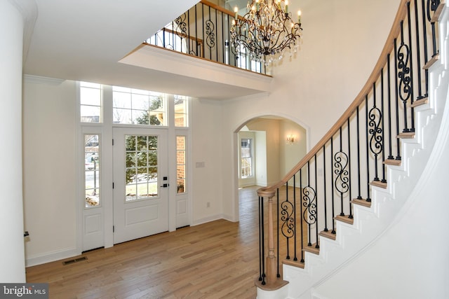 foyer with arched walkways, wood finished floors, visible vents, and baseboards