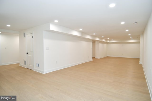 finished below grade area with baseboards, visible vents, light wood-style flooring, and recessed lighting