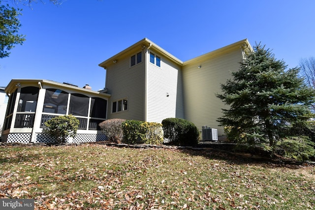 view of property exterior with central AC unit, a chimney, and a sunroom