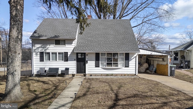 view of front of home with roof with shingles, a chimney, concrete driveway, and fence