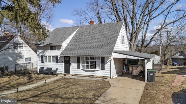 view of front facade with a shingled roof, an attached carport, fence, and a chimney