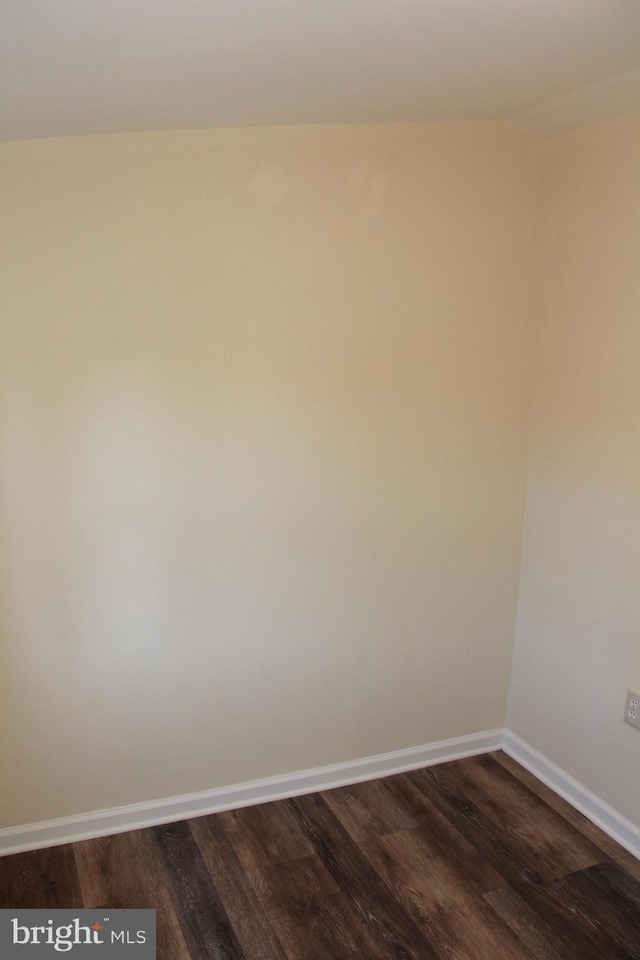 empty room featuring baseboards and dark wood finished floors