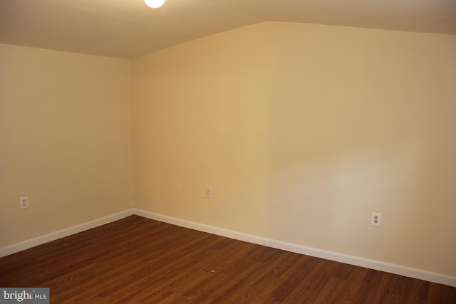 empty room featuring lofted ceiling, baseboards, and dark wood-style flooring