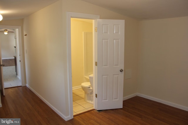 hall featuring vaulted ceiling, wood finished floors, and baseboards