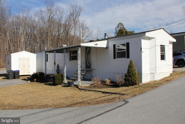 manufactured / mobile home featuring a storage unit, a front lawn, and an outdoor structure