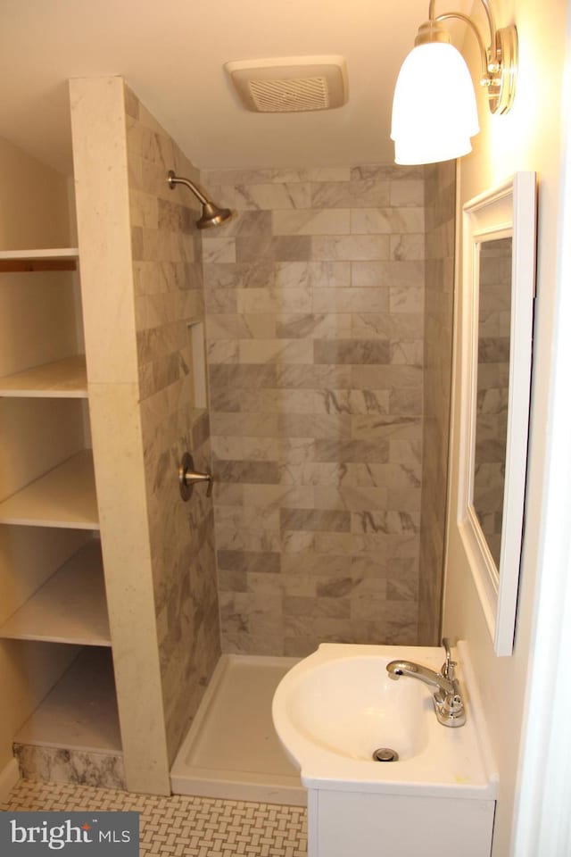 full bath with visible vents, a tile shower, and vanity