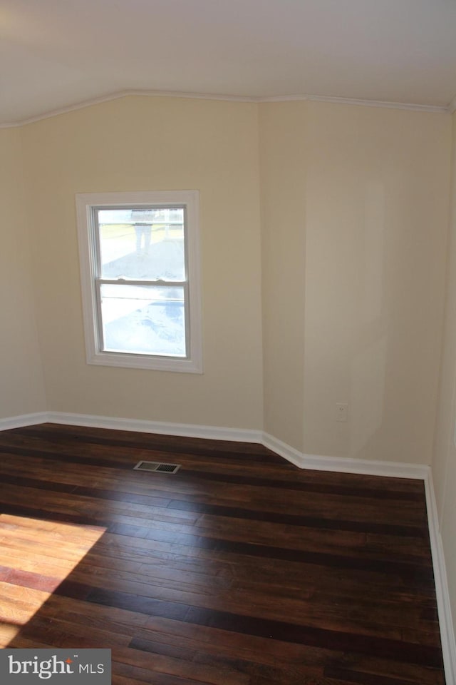 empty room featuring ornamental molding, wood finished floors, visible vents, and baseboards