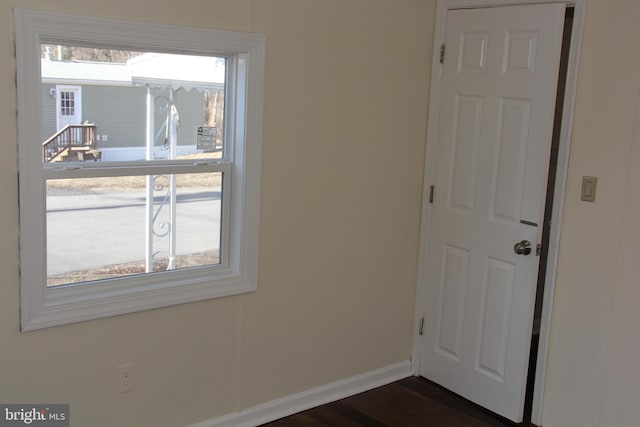 unfurnished room with dark wood-type flooring and baseboards