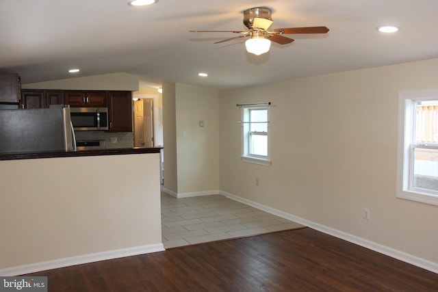 kitchen featuring appliances with stainless steel finishes, dark countertops, wood finished floors, and a wealth of natural light