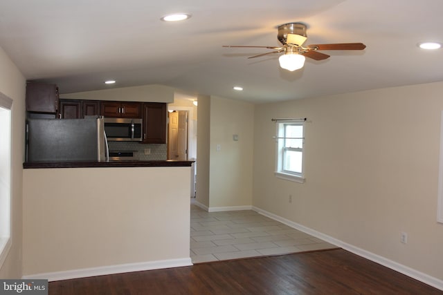 kitchen with decorative backsplash, dark countertops, appliances with stainless steel finishes, vaulted ceiling, and light wood-type flooring