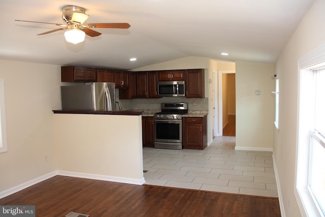 kitchen featuring light wood finished floors, tasteful backsplash, lofted ceiling, appliances with stainless steel finishes, and ceiling fan