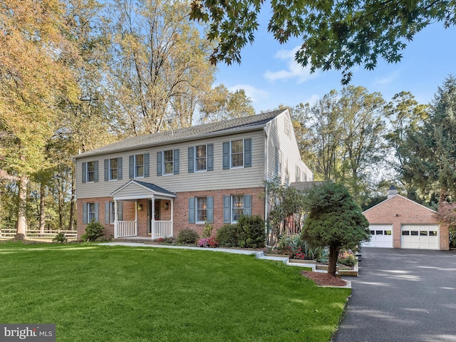 view of front of property with brick siding, a detached garage, a front lawn, and fence