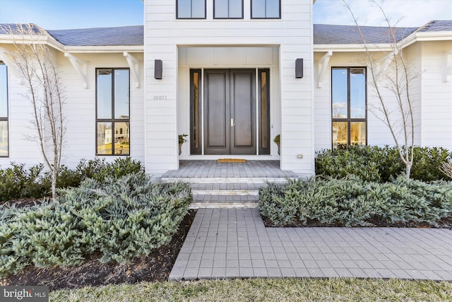 doorway to property with a shingled roof