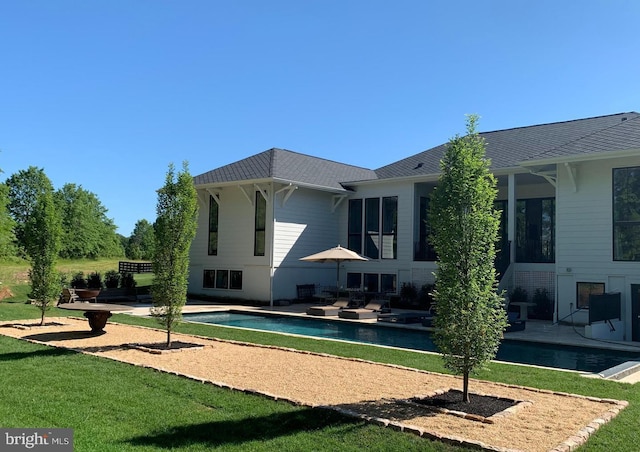 rear view of house featuring a patio, a yard, and an outdoor pool