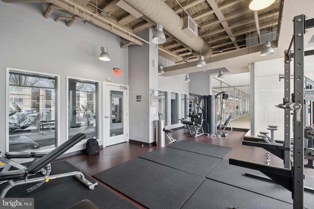 workout area featuring baseboards and a high ceiling