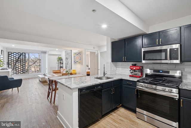 kitchen with open floor plan, stainless steel appliances, a sink, and light wood-style floors