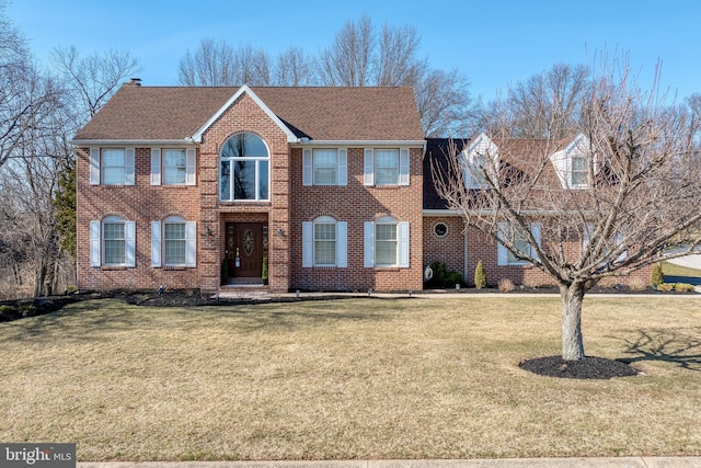 view of front of property with brick siding, a front yard, and a shingled roof