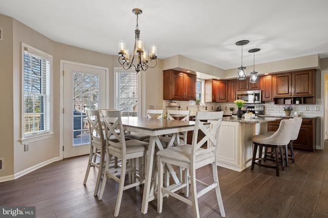 dining room with dark wood finished floors, a notable chandelier, and baseboards