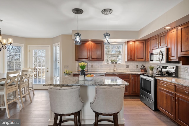 kitchen with a kitchen bar, backsplash, appliances with stainless steel finishes, and a sink