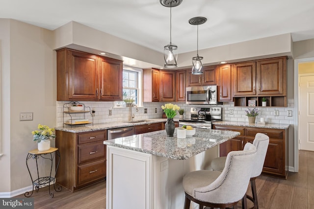 kitchen featuring a sink, backsplash, appliances with stainless steel finishes, and wood finished floors