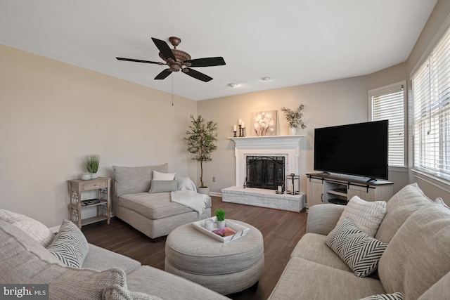 living room featuring a brick fireplace, baseboards, a ceiling fan, and wood finished floors