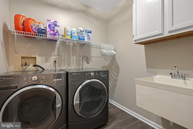 washroom featuring baseboards, cabinet space, separate washer and dryer, dark wood-style flooring, and a sink