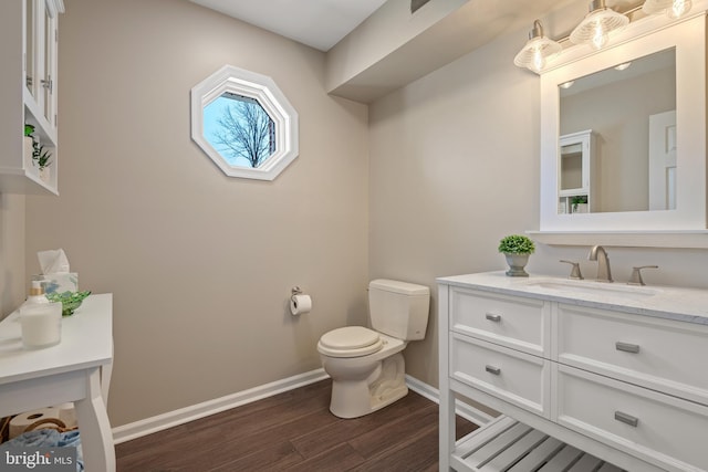 half bathroom featuring baseboards, toilet, wood finished floors, and vanity